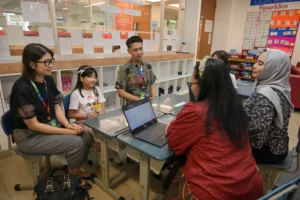 A primary student of Sekolah Victory Plus, together with her parents, and teachers, setting up goals during the PYP Three-Way Conference.