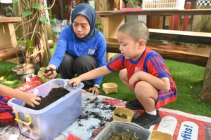 A student and a teacher at Sekolah Victory Plus, an International Baccalaureate school in Indonesia, practiced sustainability by growing tomatoes.