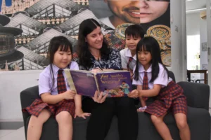 Students and a teacher of Sekolah Victory Plus, an international school in Bekasi, read a book at the school library.