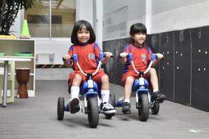 Two students of Sekolah Victory Plus, an International Baccalaureate School in Bekasi, excitedly ride bicycles at school.