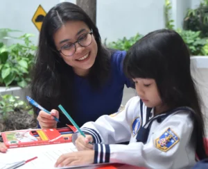 Ibu membantu anaknya mengerjakan tugas sekolah dengan senyum hangat.