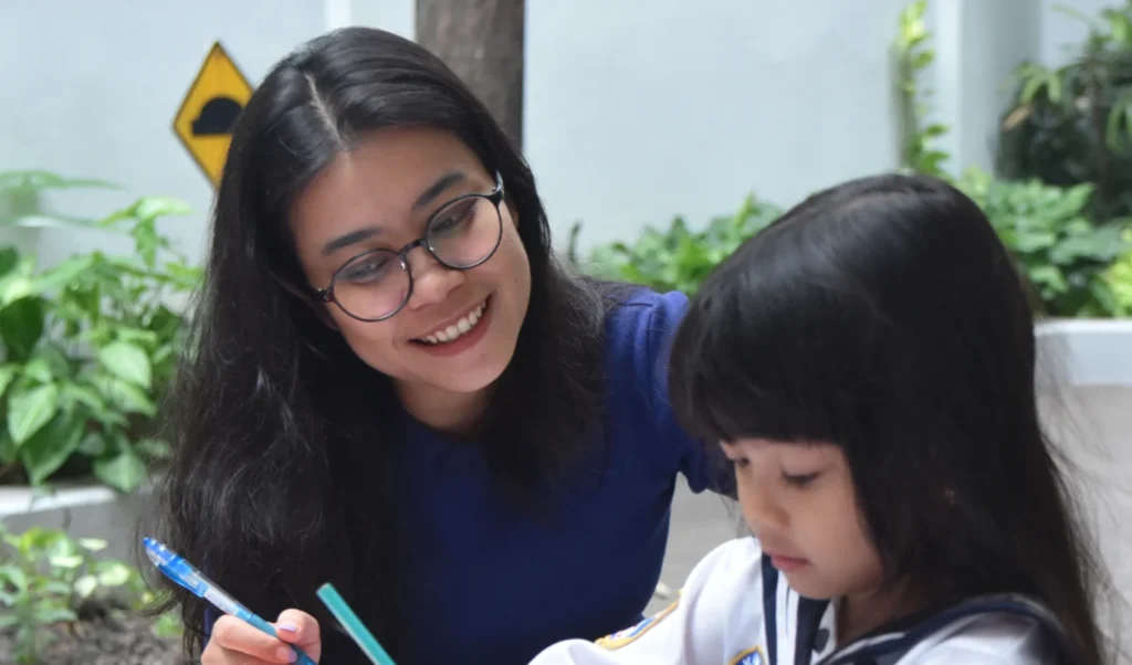 Ibu membantu anaknya mengerjakan tugas sekolah dengan senyum hangat.