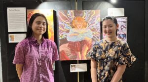 Grade 11 students standing in front of the paintings during the Mini Visual Arts and Music Exhibition at Sekolah Victory Plus, an international school in Indonesia.