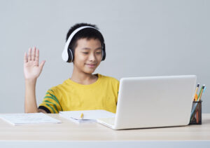 a boy studying using headphones and a laptop.