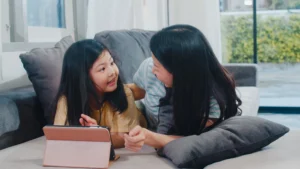 A mother and her daughter watch a video using a tablet, looking fun and lovely.