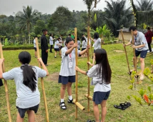 Students are learning to play Egrang, a traditional game, during the Learning Beyond the Walls activity.