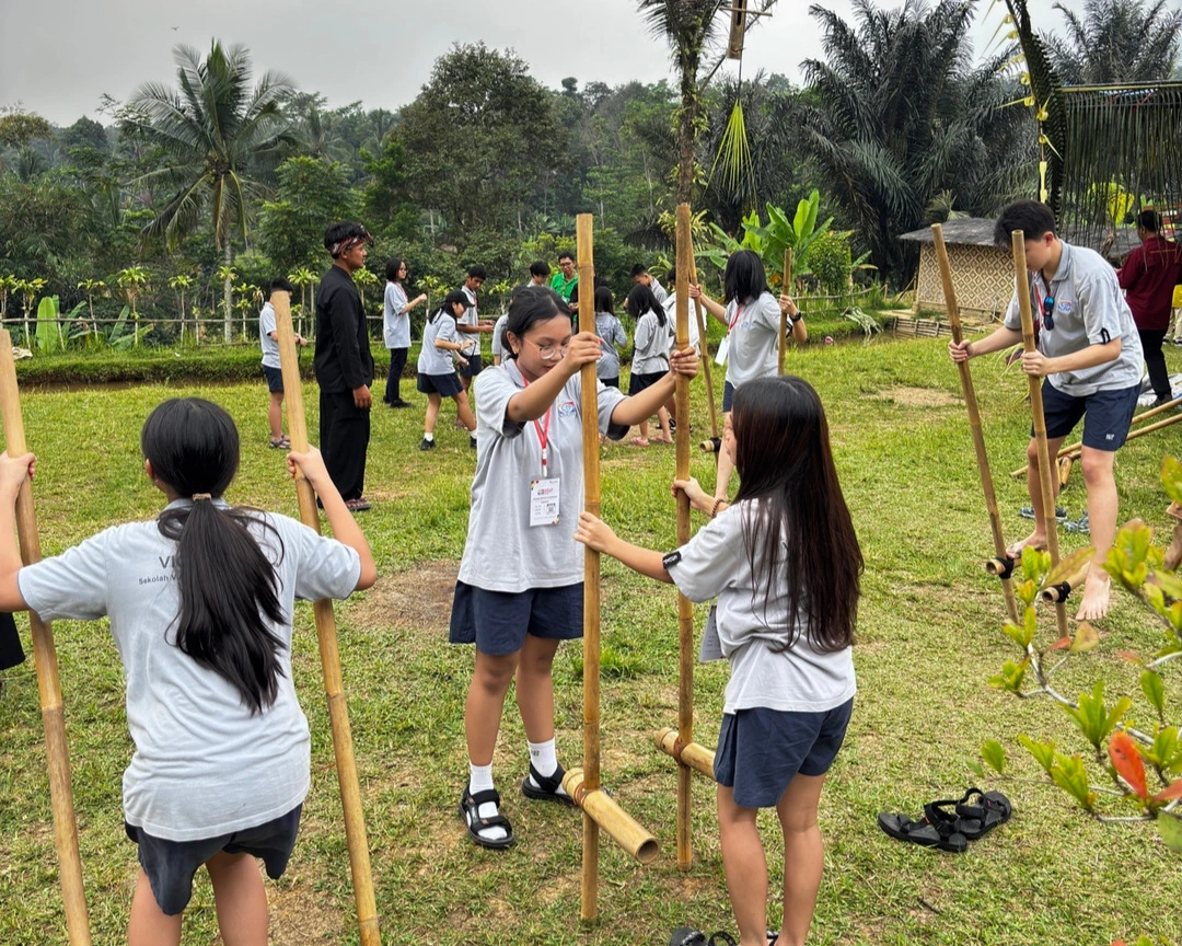 Students are learning to play Egrang, a traditional game, during the Learning Beyond the Walls activity.